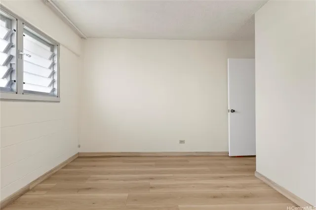 a view of an empty room with wooden floor and windows