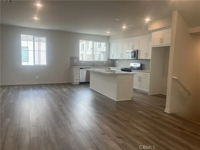 a kitchen with stainless steel appliances granite countertop a refrigerator a sink dishwasher a stove and white countertops with wooden floor