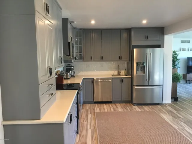 a kitchen with stainless steel appliances granite countertop a refrigerator a sink dishwasher and a stove with wooden floor