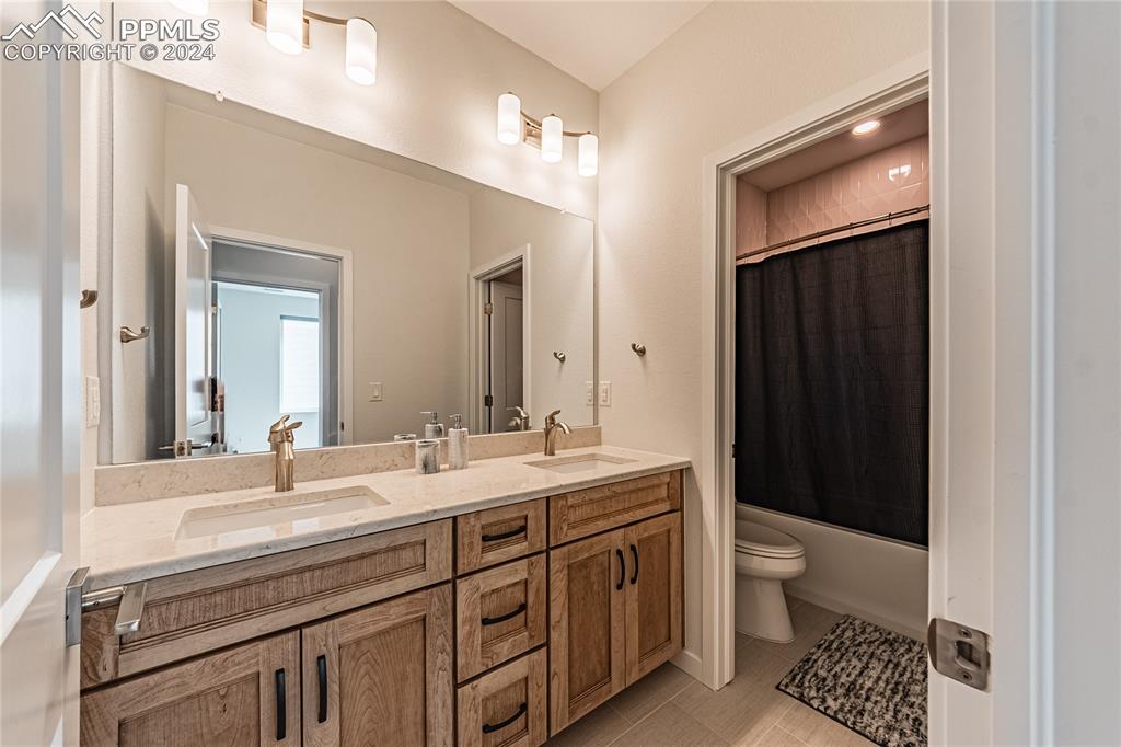 11148 Cloud Shadow Road Littleton, CO 80125 - Photo 25 of 46 a bathroom with a double vanity sink a toilet and a mirror