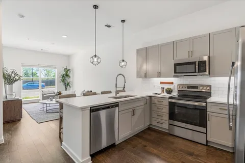 a kitchen with stainless steel appliances granite countertop a sink a stove and a wooden floors