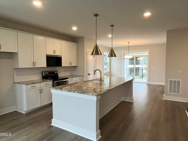 a large kitchen with stainless steel appliances granite countertop a sink a stove and a wooden floors