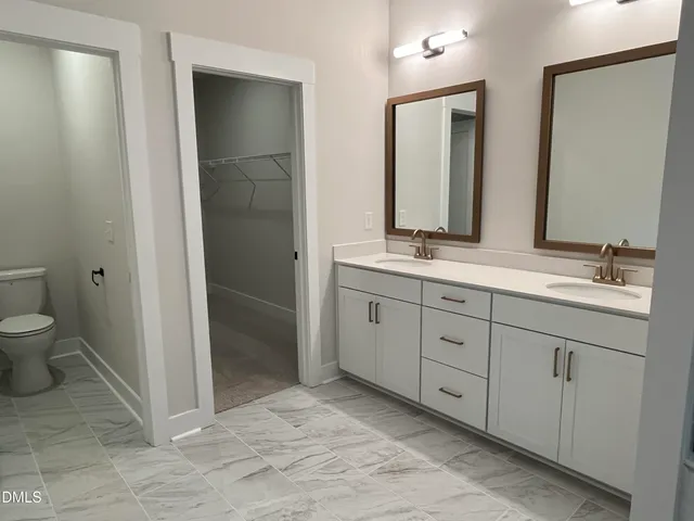 a spacious bathroom with a double vanity sink mirror and toilet