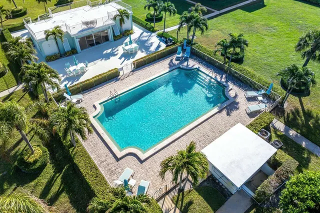 a view of a small pool with lawn chairs and plants