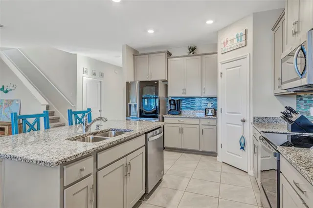 a kitchen with granite countertop a sink stainless steel appliances and white cabinets