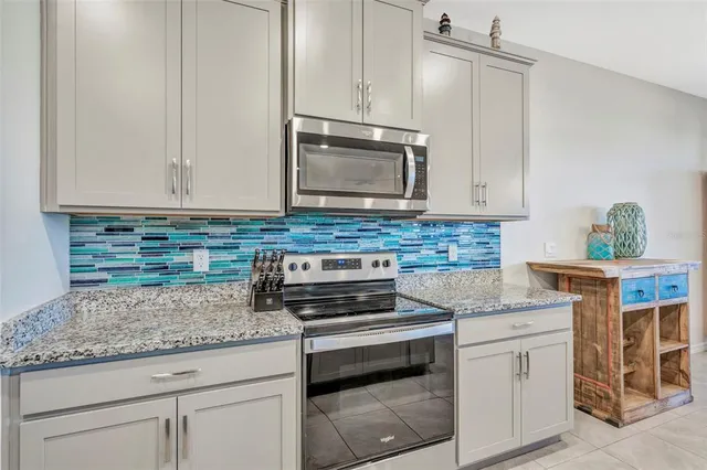 a kitchen with granite countertop a sink stove and microwave