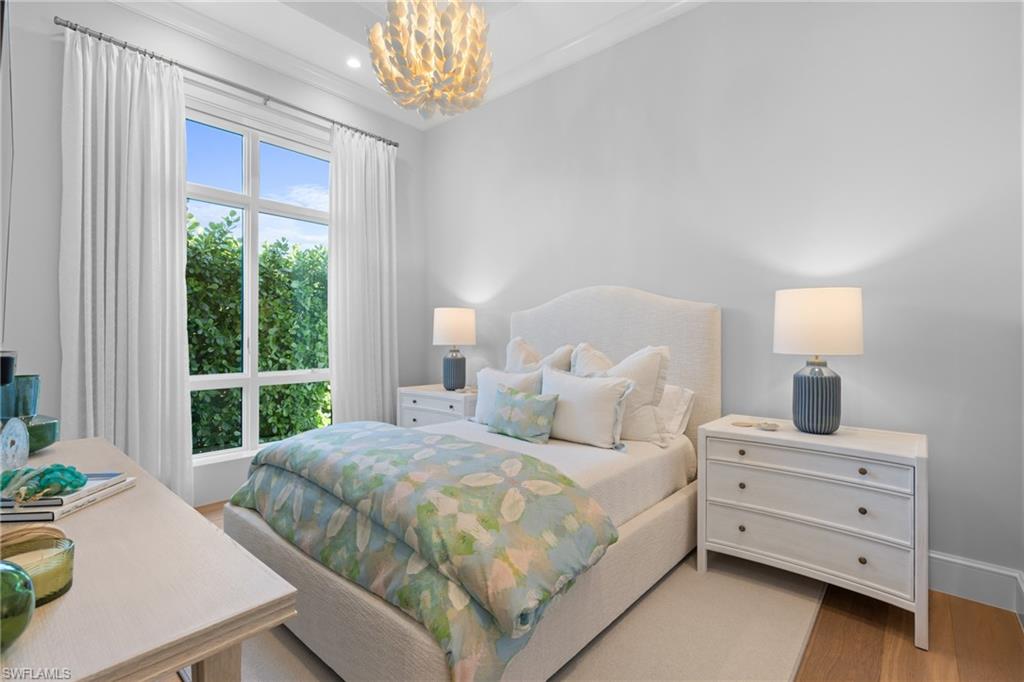 4511 Crayton Road Naples, FL 34103 - Photo 19 of 28 a bedroom with a bed a chandelier and a window