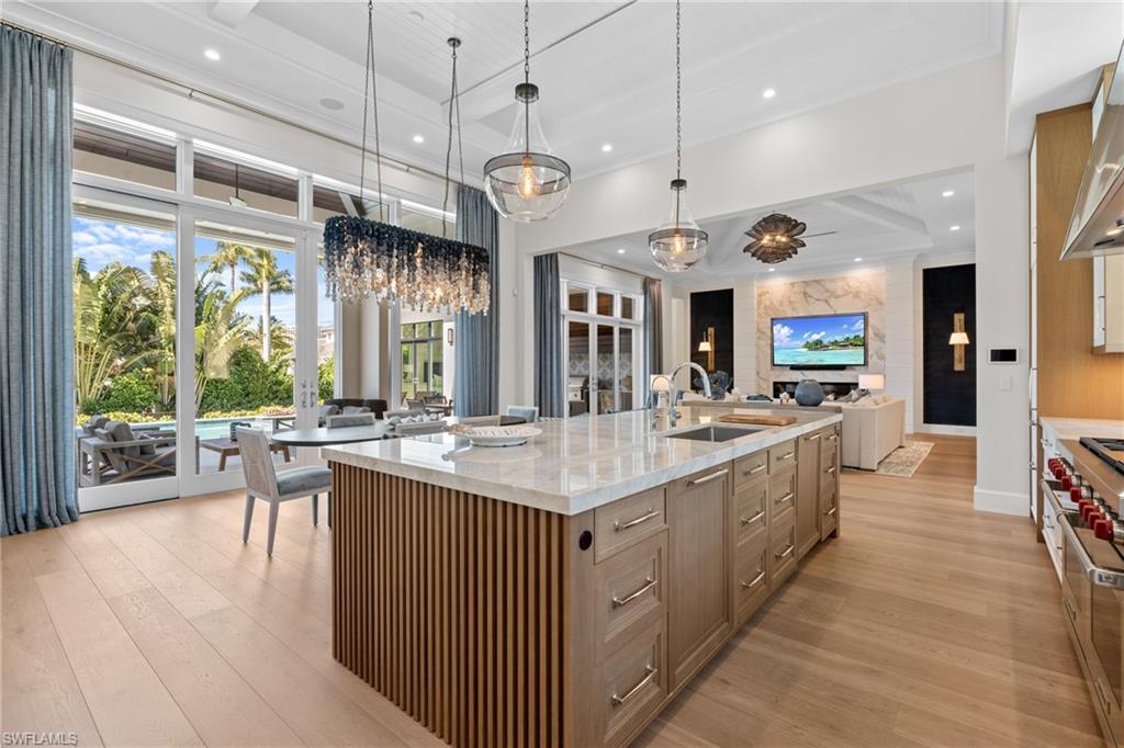 4511 Crayton Road Naples, FL 34103 - Photo 6 of 28 a large kitchen with stainless steel appliances kitchen island granite countertop a large kitchen island a stove a sink a refrigerator and a view of living room