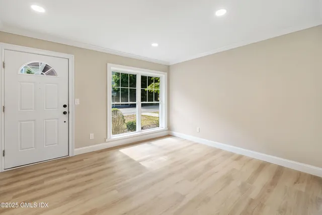 a view of an empty room with wooden floor and windows