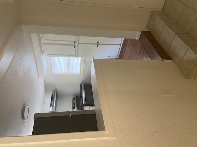 417 South Commerce Street, Unit B Lockhart, TX 78644 - Photo 5 of 9 Kitchen with stainless steel appliances, a textured ceiling, dark tile patterned floors, a peninsula, and white cabinets