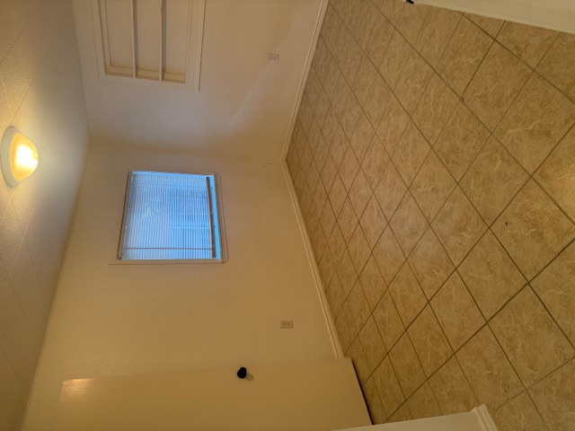 417 South Commerce Street, Unit B Lockhart, TX 78644 - Photo 7 of 9 Bedroom 2 with built in features, a textured ceiling, and tile floors. This room also has a half bathroom