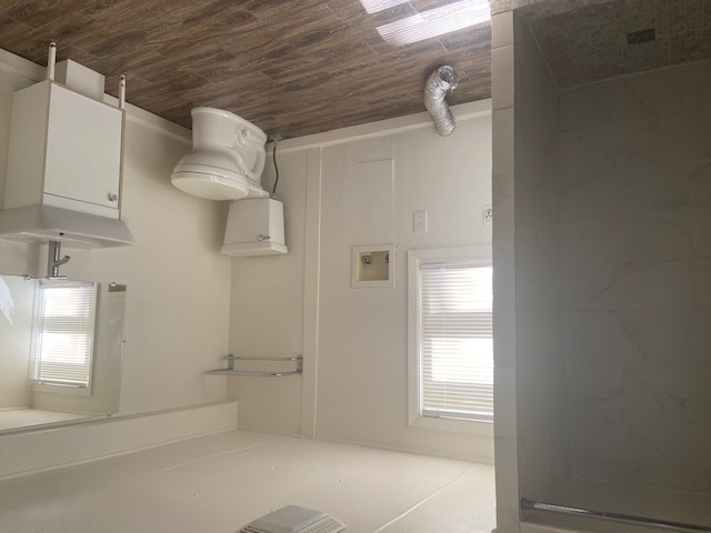 417 South Commerce Street, Unit B Lockhart, TX 78644 - Photo 9 of 9 Full bath featuring vanity, dark wood-style flooring, a tile shower, and healthy amount of natural light. Their are also washer/dryer connections in this bathroom for tenant to bring their own units