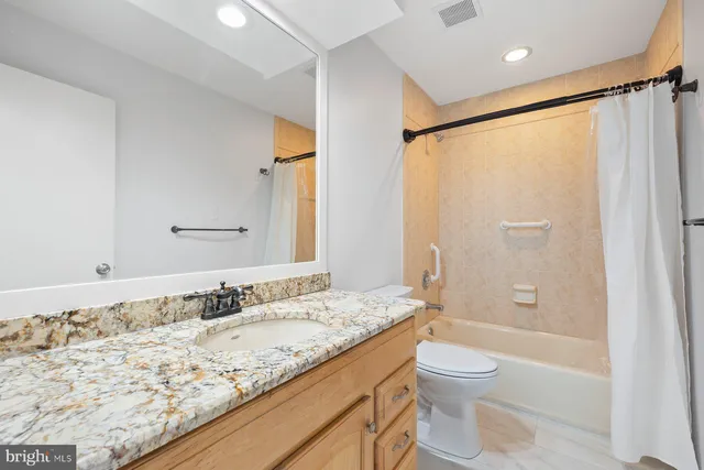 a bathroom with a granite countertop sink toilet and shower