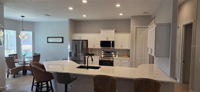 a kitchen with stainless steel appliances granite countertop a refrigerator a stove a sink a dining table and chairs