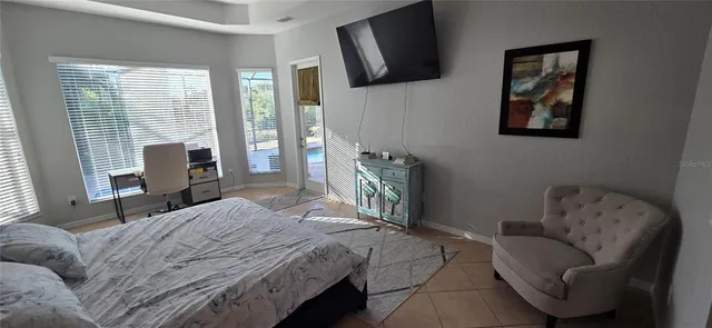 a bedroom with a bed couch and a flat tv screen on the dresser