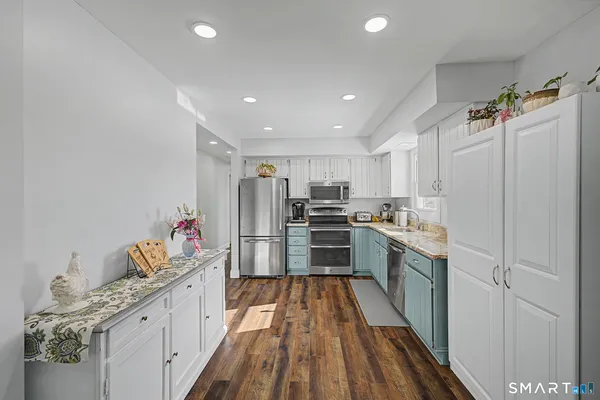 a kitchen with granite countertop a refrigerator stove top oven and sink