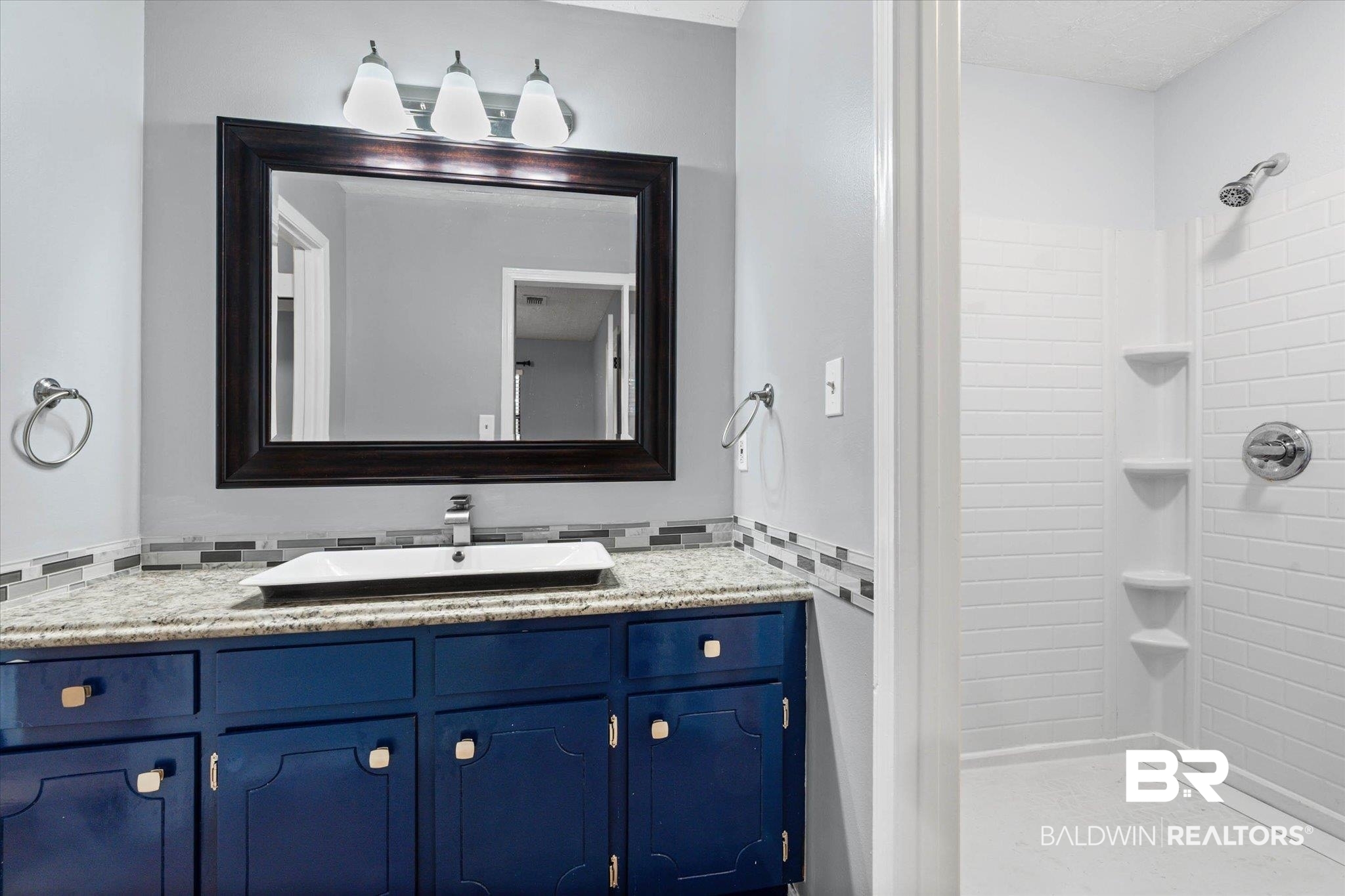 500 Grant Street, Unit C210 Daphne, AL 36526 - Photo 18 of 26 Bathroom featuring a blue vanity with a granite-style countertop, a vessel sink with a chrome faucet, and a large framed mirror with a three-light fixture