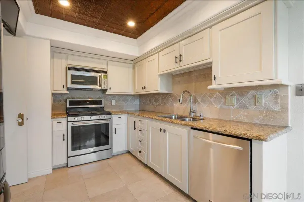 a kitchen with granite countertop a sink stove and cabinets