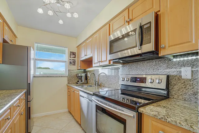 a kitchen with stainless steel appliances granite countertop a sink a stove and a refrigerator