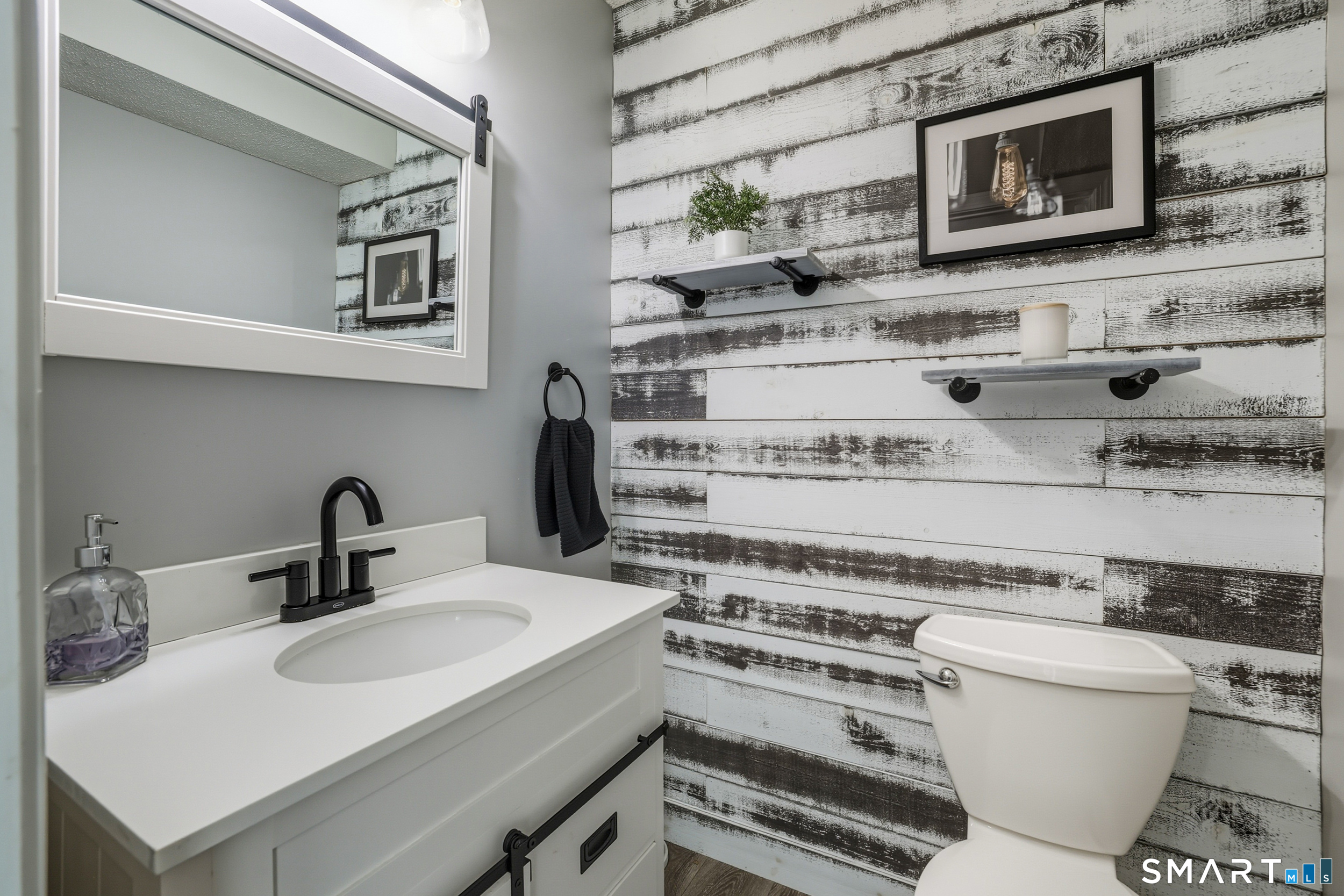 20 Wolf Hill Road, Unit 1A Wolcott, CT 06716 - Photo 16 of 36 Remodeled half bath with wood accented wall, vanity with barn door cabinet and quartz countertop