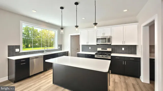 a kitchen with stainless steel appliances granite countertop a sink a stove a refrigerator and a window with wooden floors
