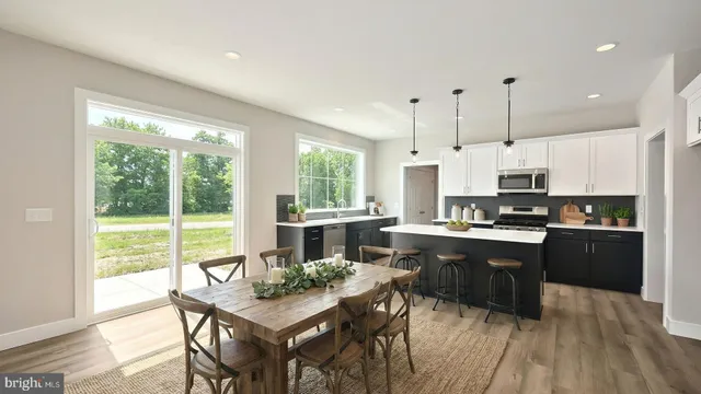 a open kitchen with stainless steel appliances granite countertop a stove a refrigerator a kitchen island a table and chairs with wooden floor