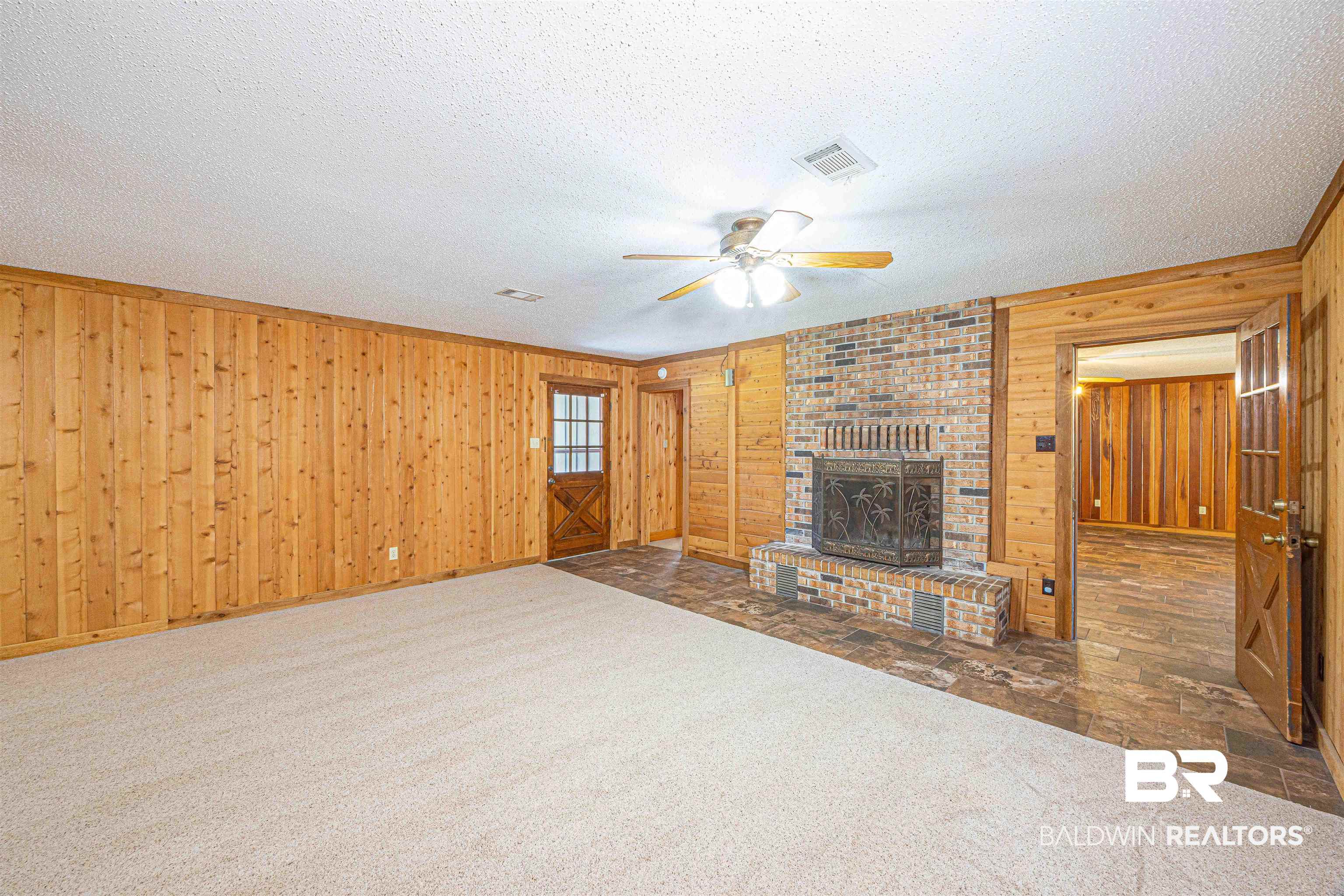 43101 Brown Road Bay Minette, AL 36507 - Photo 25 of 81 Unfurnished living room with a ceiling fan, dark colored carpet, wood walls, a fireplace, and a textured ceiling
