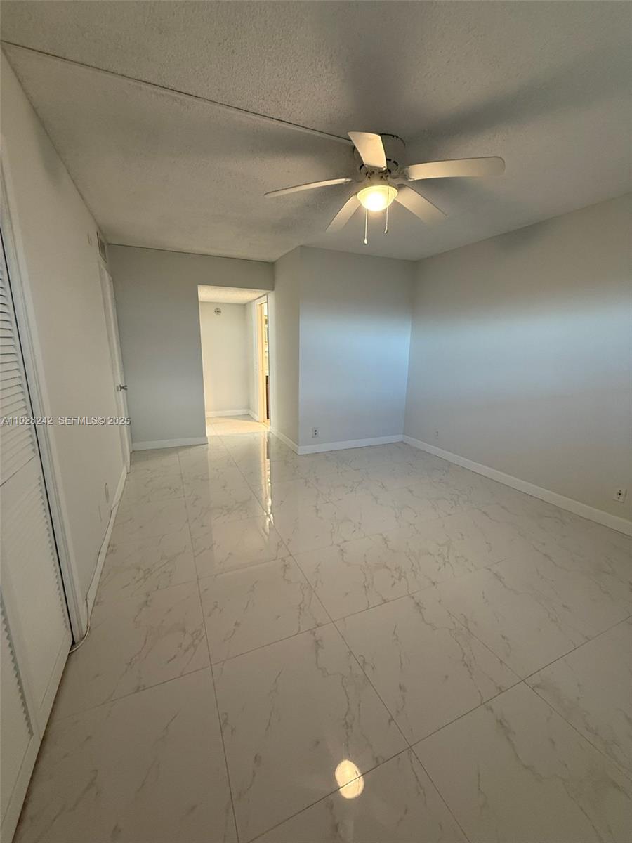 3091 North Course Drive, Unit 705 Pompano Beach, FL 33069 - Photo 12 of 30 an empty room with a ceiling fan and a window