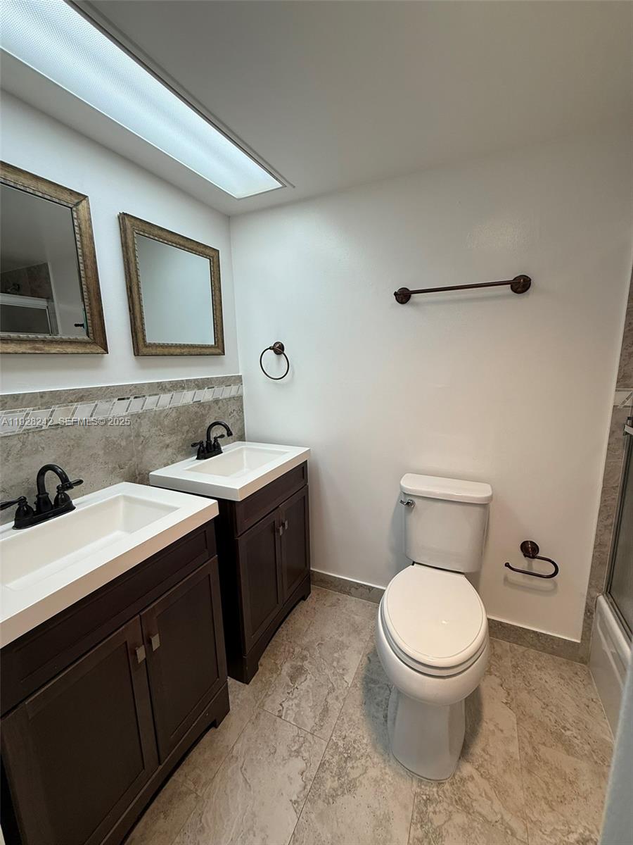 3091 North Course Drive, Unit 705 Pompano Beach, FL 33069 - Photo 14 of 30 a bathroom with a toilet sink a mirror and vanity
