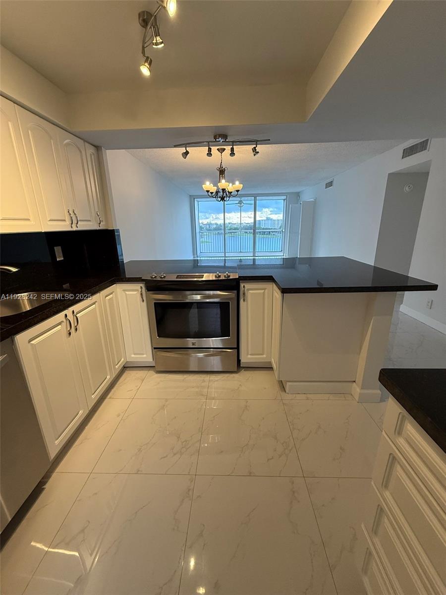 3091 North Course Drive, Unit 705 Pompano Beach, FL 33069 - Photo 20 of 30 a kitchen with stainless steel appliances a stove a microwave and white cabinets