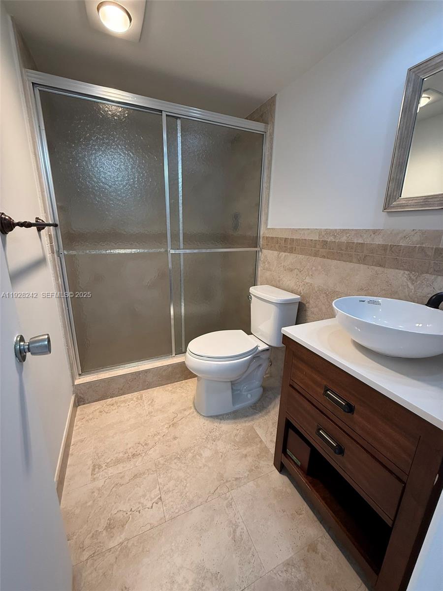 3091 North Course Drive, Unit 705 Pompano Beach, FL 33069 - Photo 26 of 30 a bathroom with a granite countertop sink toilet and a shower