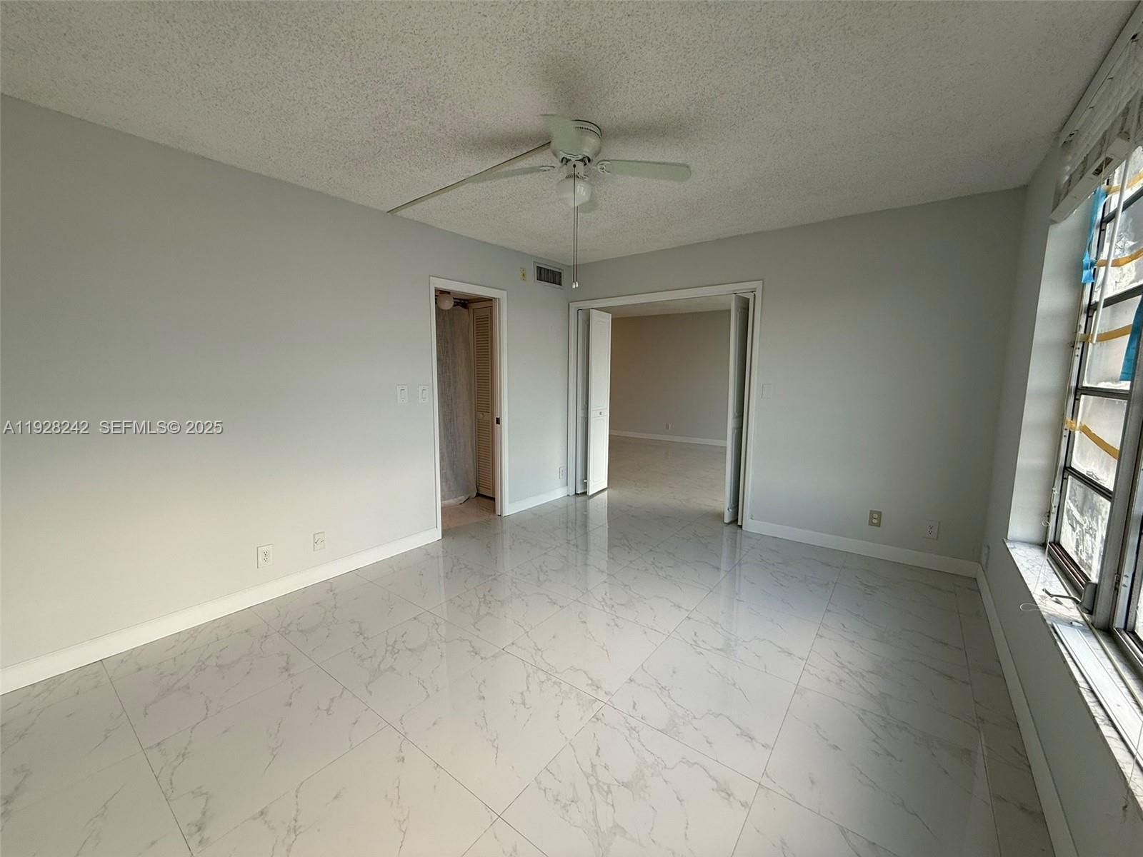 3091 North Course Drive, Unit 705 Pompano Beach, FL 33069 - Photo 27 of 30 an empty room with windows and ceiling fan
