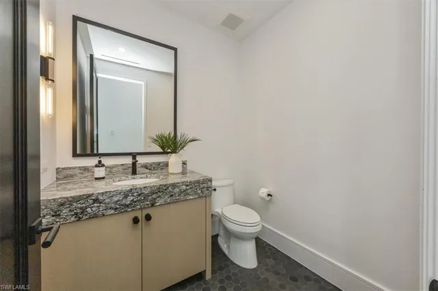 a bathroom with a granite countertop toilet sink and mirror