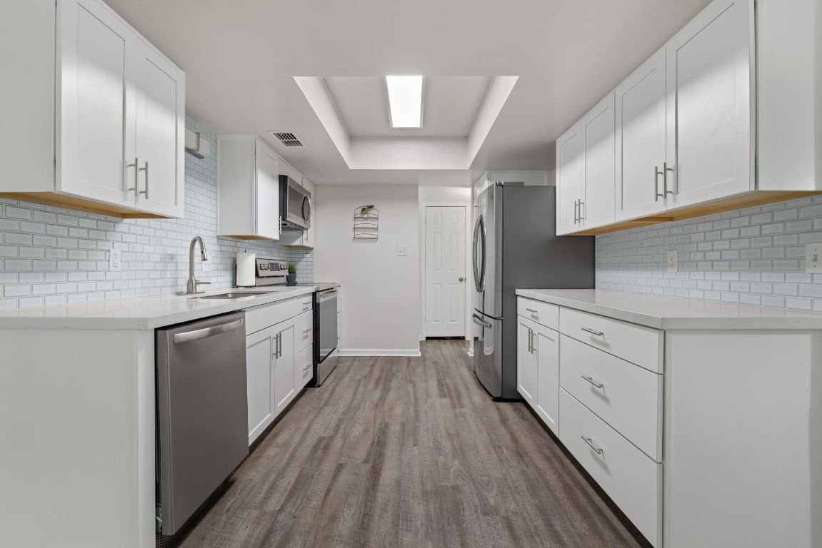 8906 Trone Circle, Unit A Austin, TX 78758 - Photo 11 of 33 a kitchen with cabinets wooden floor and stainless steel appliances