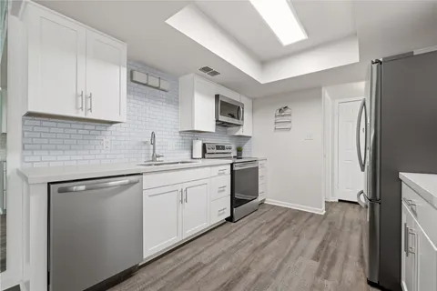 a kitchen with cabinets wooden floor and stainless steel appliances