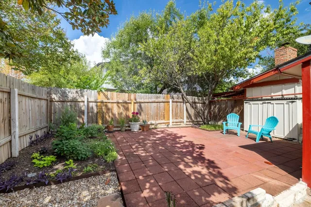 a backyard of a house with a table and chairs under an umbrella