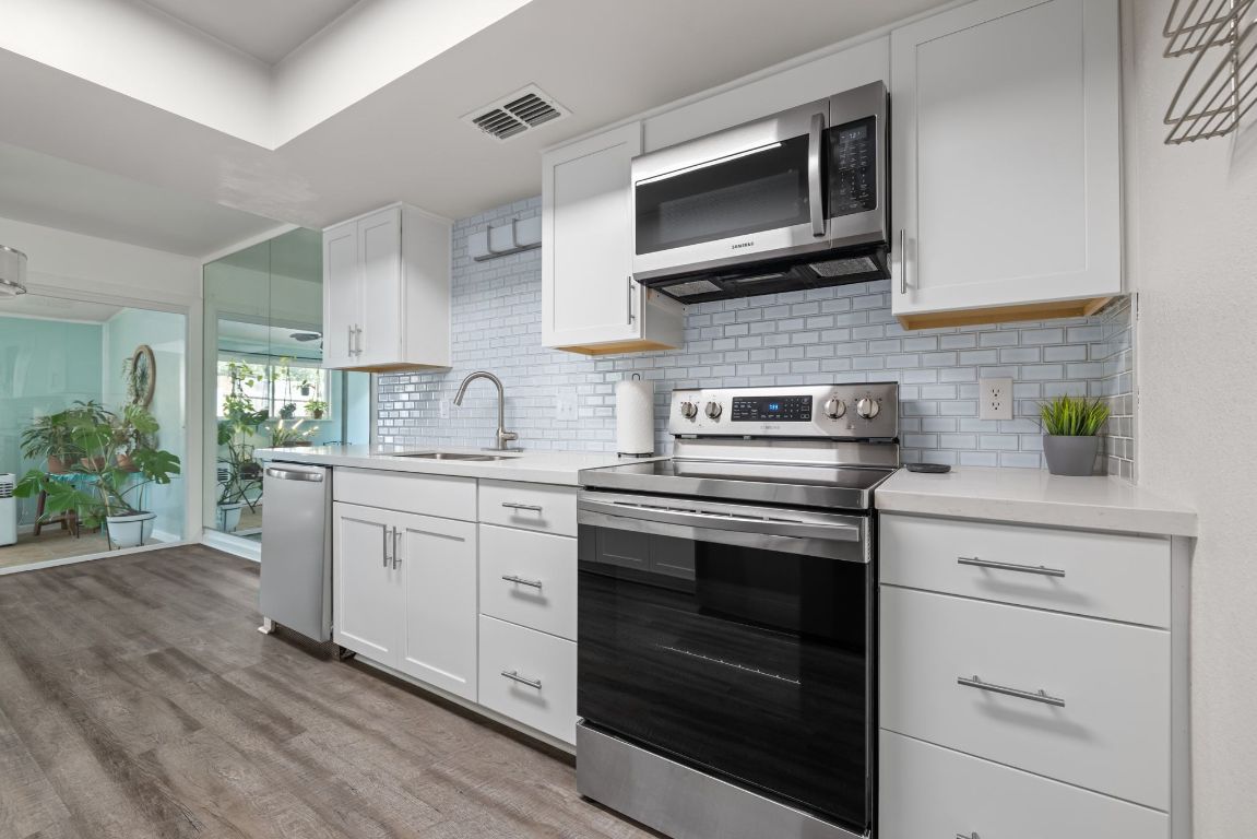 8906 Trone Circle, Unit A Austin, TX 78758 - Photo 10 of 33 a kitchen with stainless steel appliances white cabinets and stove top oven