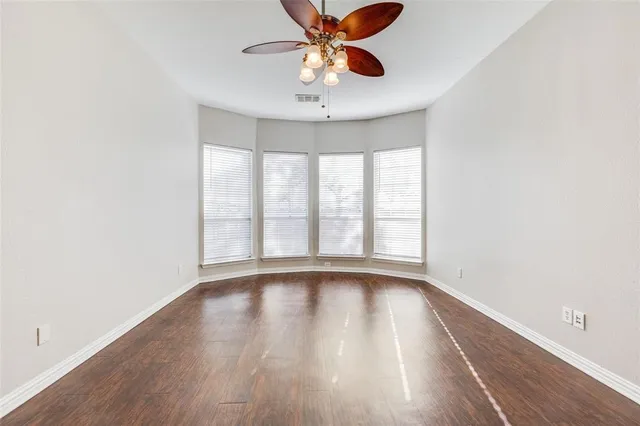 a view of an empty room with window and wooden floor