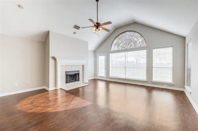an empty room with wooden floor fireplace and windows