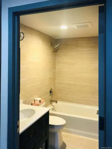 a bathroom with a bathtub shower sink vanity and toilet