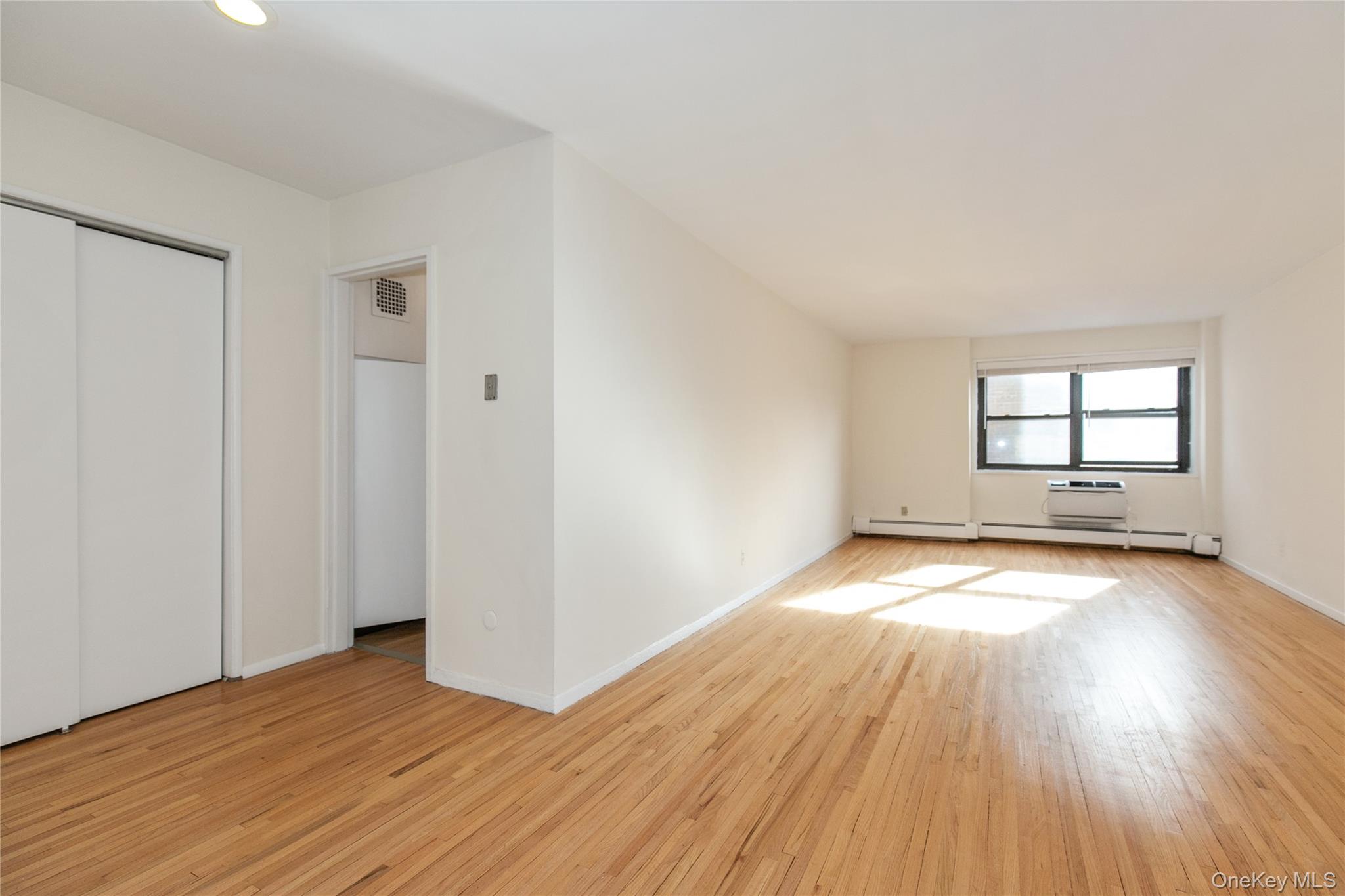 25 Park Place, Unit 2G Great Neck, NY 11021 - Photo 3 of 20 an empty room with wooden floor and windows