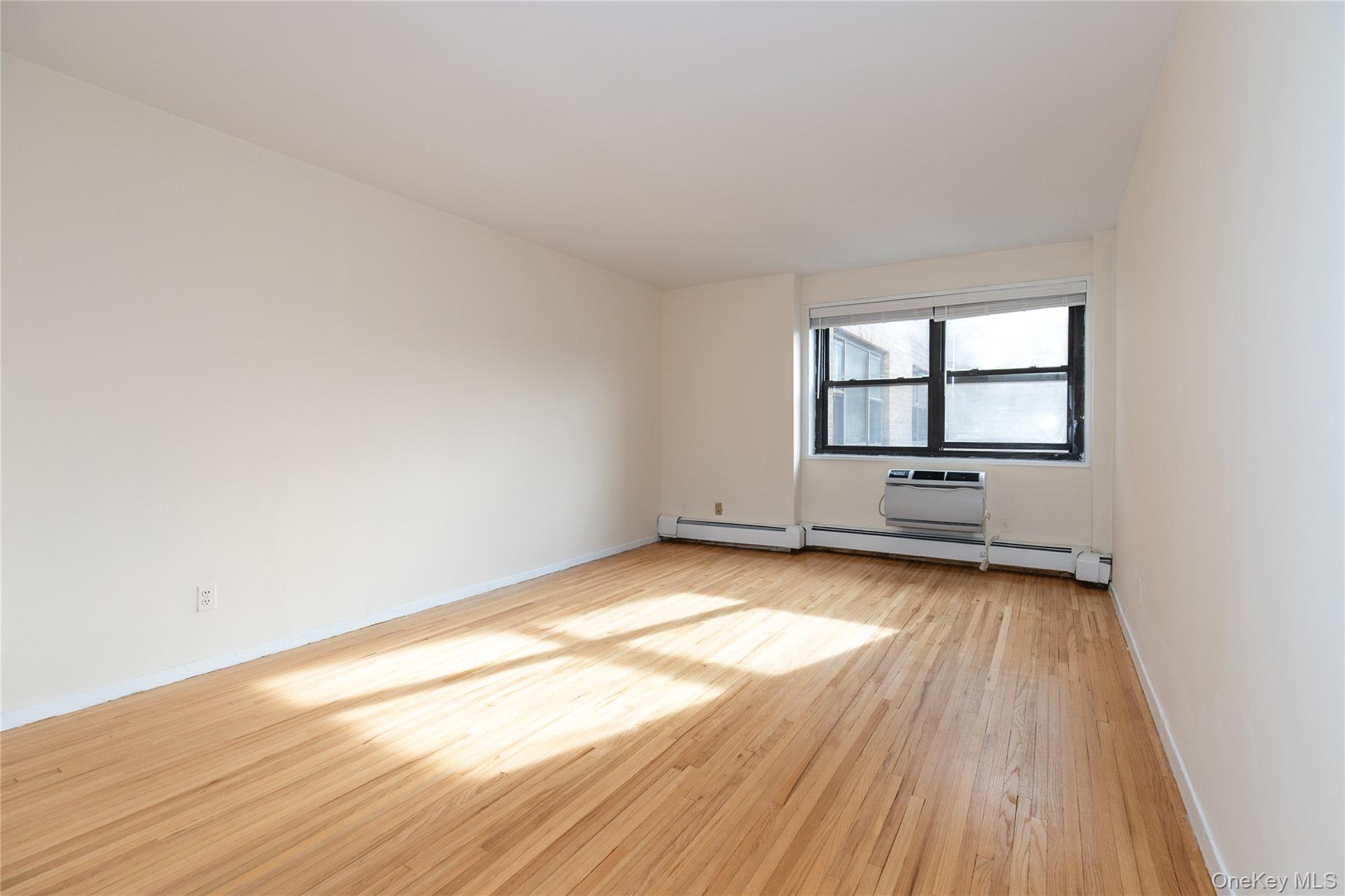 25 Park Place, Unit 2G Great Neck, NY 11021 - Photo 7 of 20 an empty room with wooden floor and windows