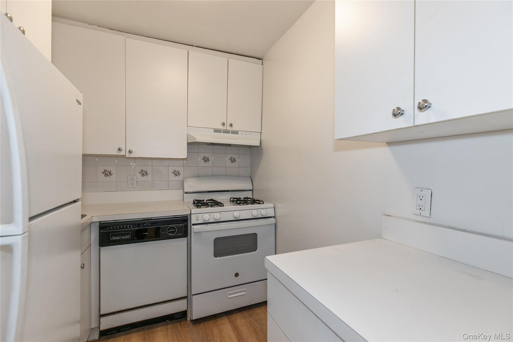 25 Park Place, Unit 2G Great Neck, NY 11021 - Photo 9 of 20 a kitchen with white cabinets and white appliances