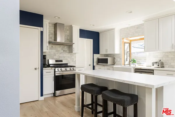 a kitchen with a stove a refrigerator a sink and dishwasher with wooden floor