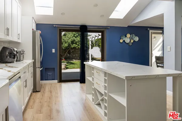 a kitchen with stainless steel appliances a stove a sink a refrigerator white cabinets and wooden floor