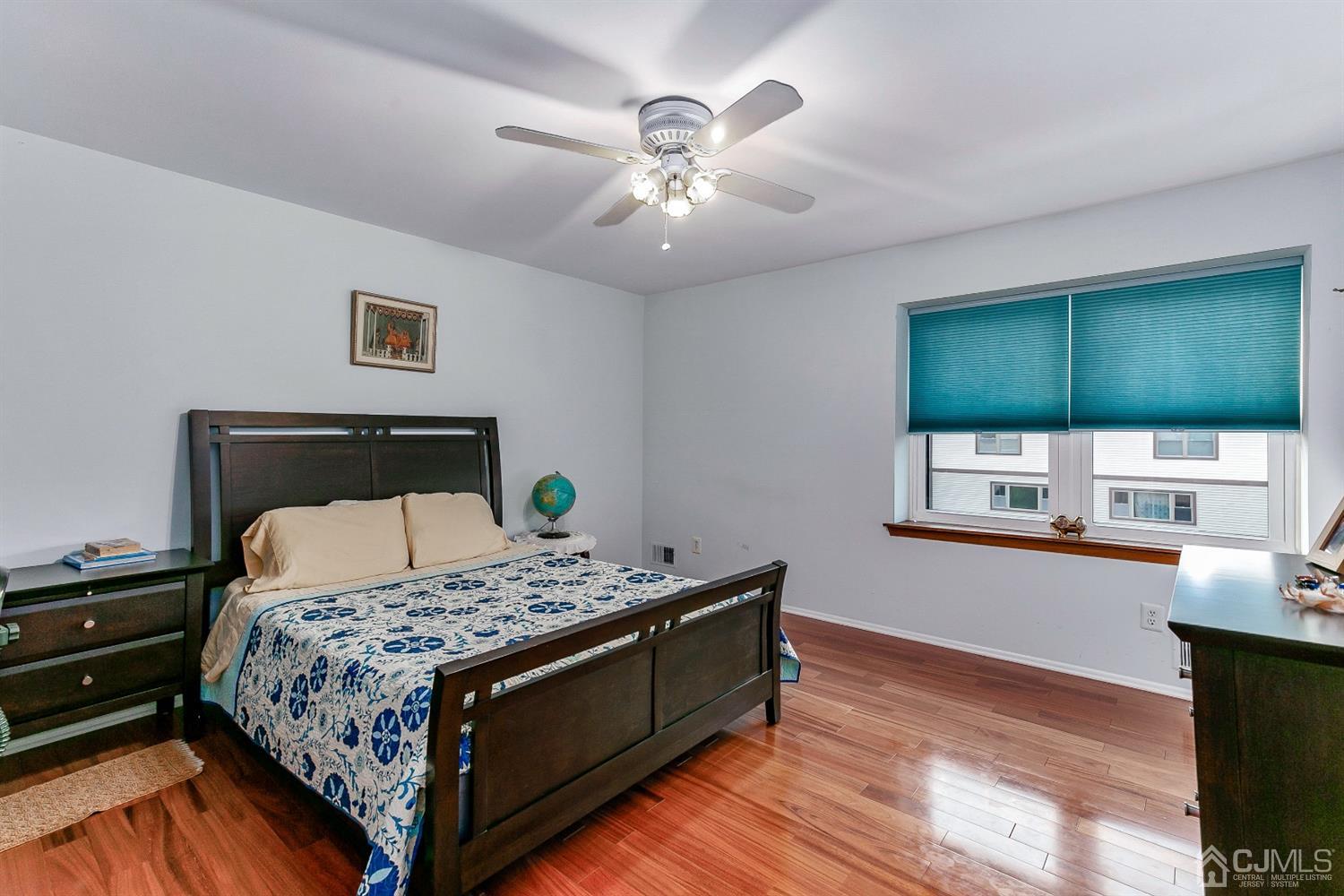 7303 Hana Road Edison, NJ 08817 - Photo 18 of 24 a bedroom with a bed and a dresser with wooden floor
