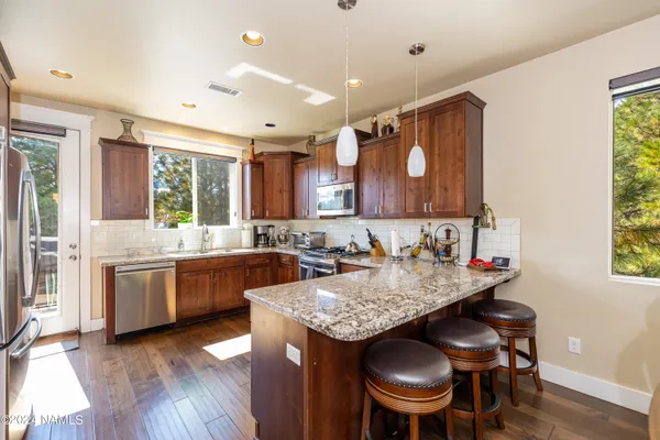a kitchen with granite countertop a sink a stove a counter space and chairs