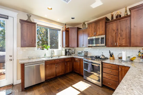 a kitchen with stainless steel appliances granite countertop wooden cabinets sink and stove top oven