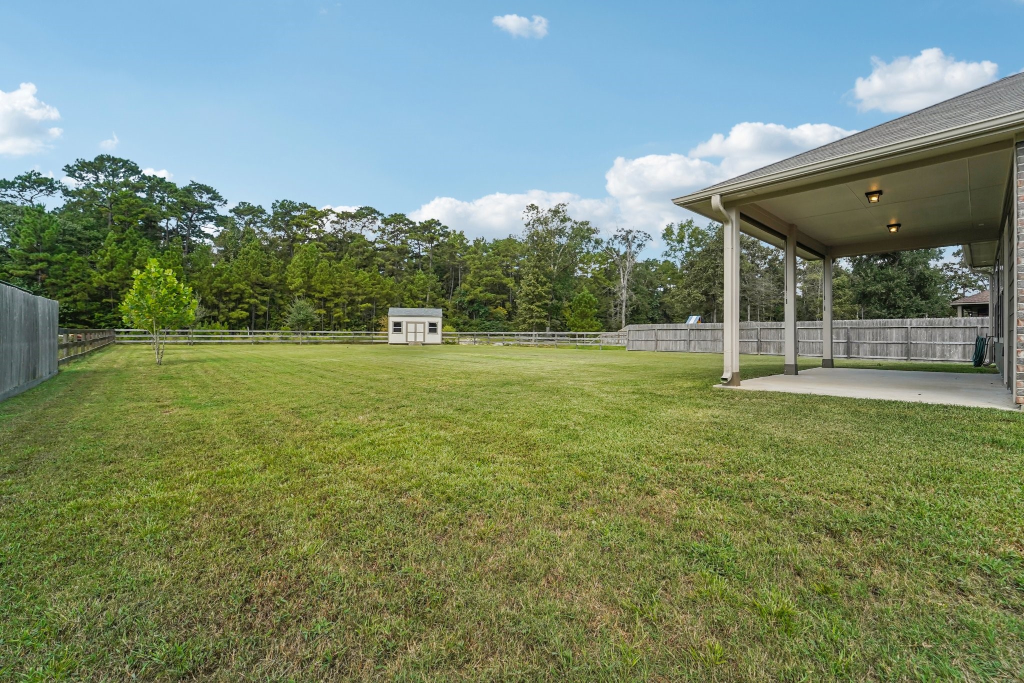 4542 Coues Deer Lane Conroe, TX 77303 - Photo 42 of 50 Expansive backyard with lush green lawn, perfect for outdoor activities and relaxation. Features a covered patio for entertaining and a storage shed for added convenience.