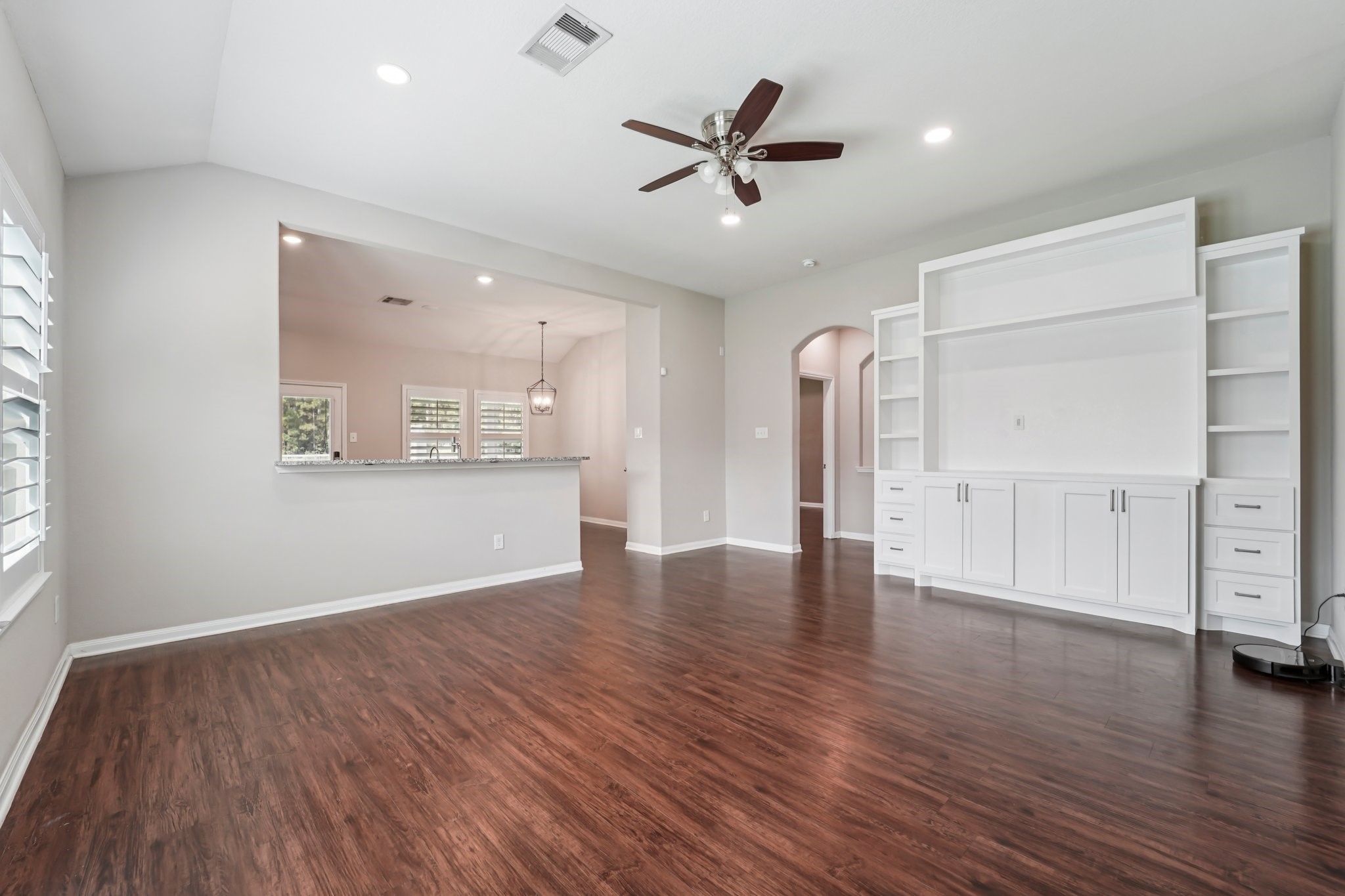 4542 Coues Deer Lane Conroe, TX 77303 - Photo 6 of 50 This spacious living room boasts elegant hardwood floors, abundant natural light, and a built-in entertainment center, seamlessly flowing into an open kitchen area perfect for entertaining.